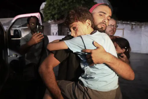 Palestinians help wounded children in an Israeli bombardment on the Gaza Strip to Al Aqsa hospital in Deir al Balah, central Gaza Strip, late on Thursday. l Photo: AFP