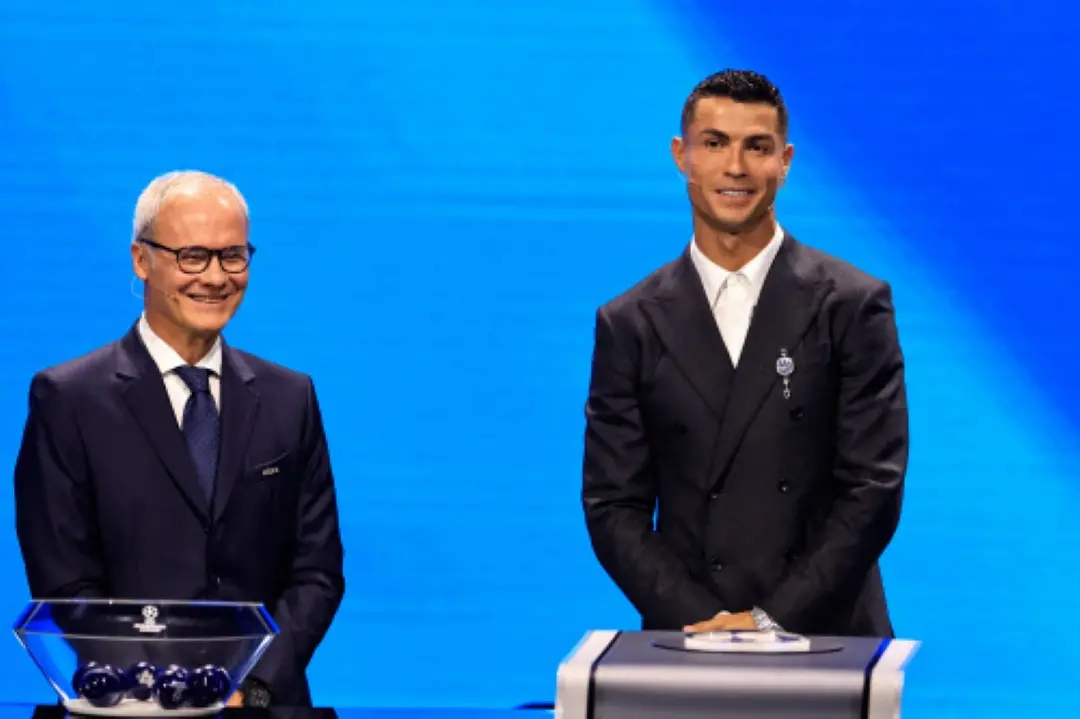UEFA Deputy General Secretary Giorgio Marchetti (L) and Portugal's national team player and Saudi Al-Nassr's forward Cristiano Ronaldo stand on the stage during the ceremony of the draw for the group stage of the 2024-2025 UEFA Champions League football tournament, at the Grimaldi Forum in Monaco. | Photo: AFP