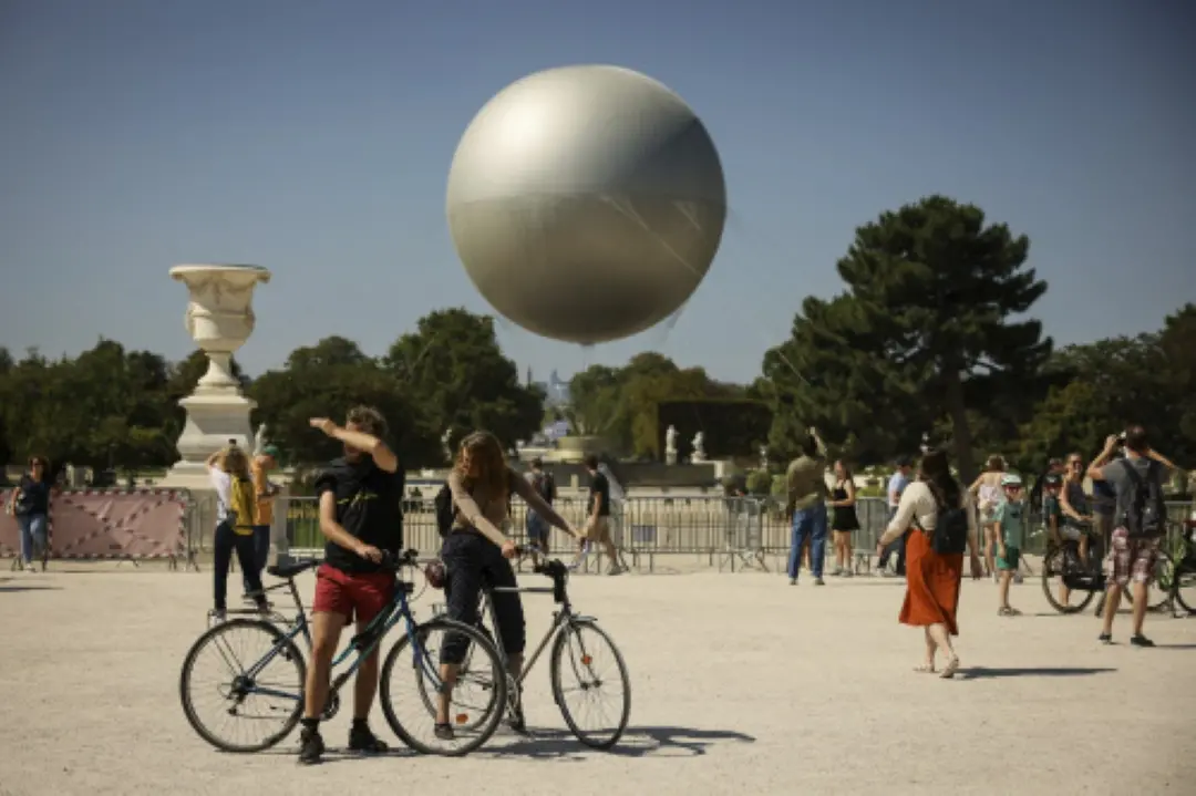People stroll past Paralympic cauldron in the Tuileries Gardens on the eve of the Paralympic Games opening ceremony in Paris. | Photo: AP