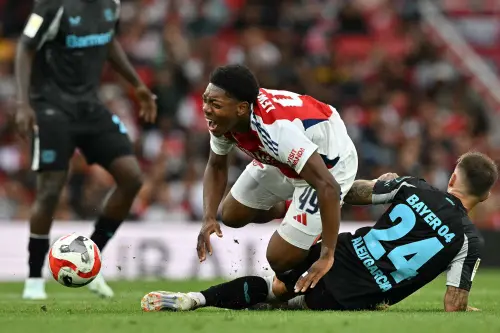 Arsenal's English midfielder #49 Myles Lewis-Skelly (C) reacts after being tackled by Bayer Leverkusen's Spanish midfielder #24 Aleix Garcia (R) during the pre-season friendly football match between Arsenal and Bayer 04 Leverkusen at the Emirates Stadium in London. | Photo: AFP