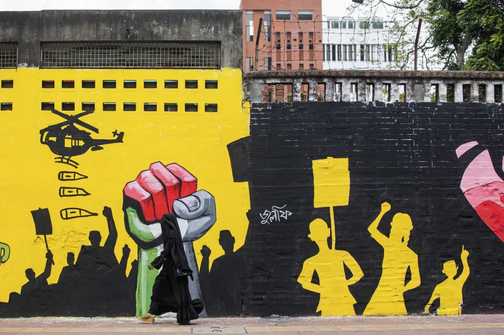A woman walks past a graffiti at Dhaka University campus area in Dhaka, Bangladesh