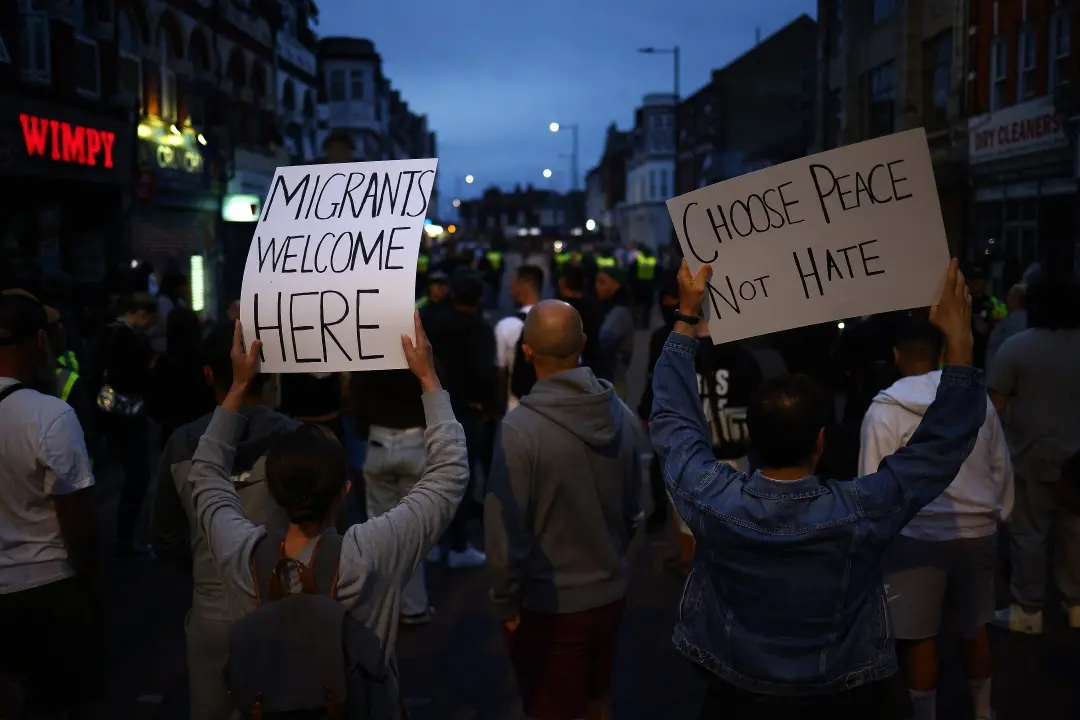 People hold anti-racism placards during a counter demonstration against an anti-immigration protest in eastern England | Photo: AFP