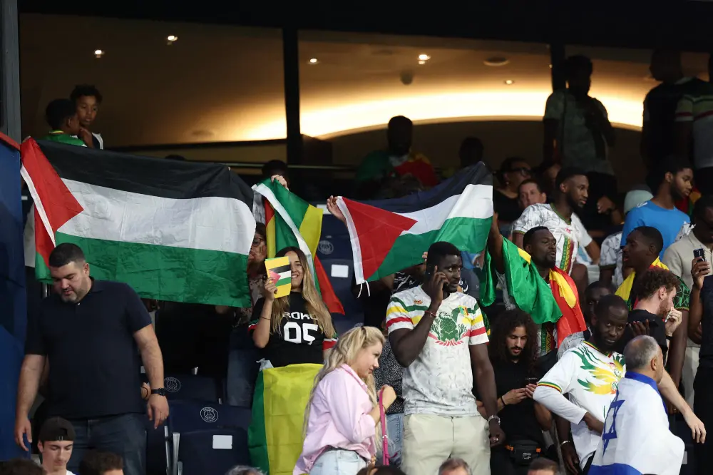 Supporters wave Palestinian flags during the men's group D football match between Mali and Israel | AFP