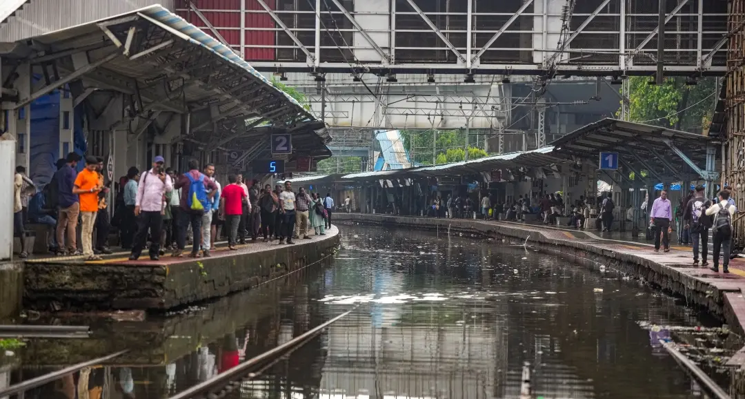 Passengers wait for trains at a waterlogged railway station | Photo: PTI