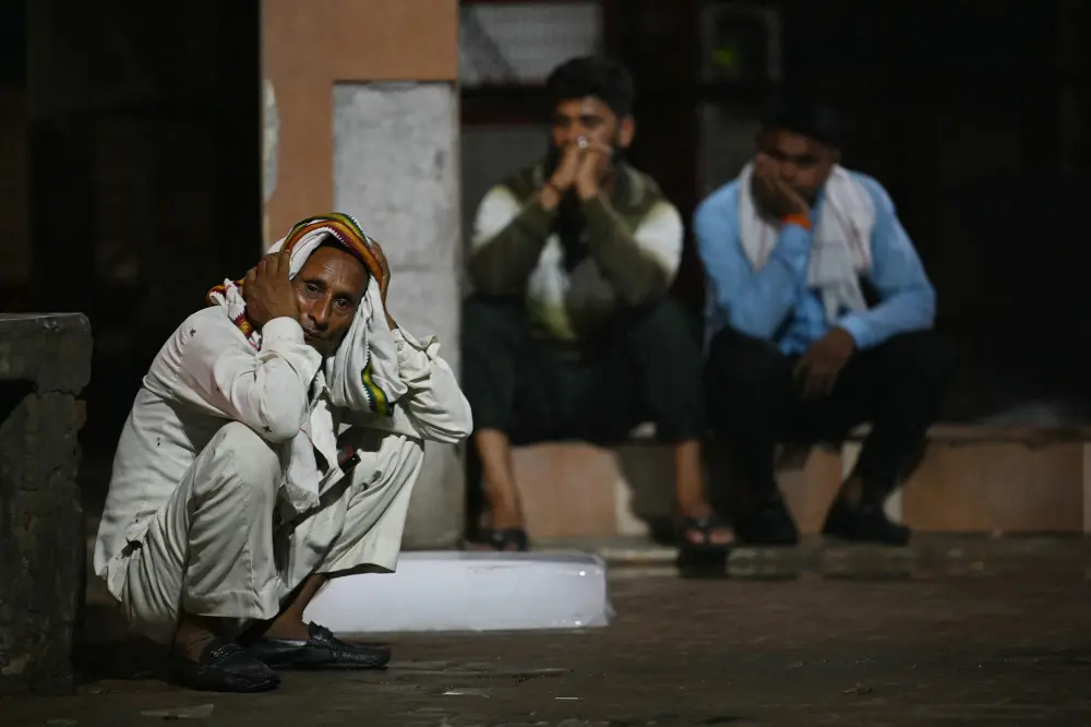 A relative (L) grieves the dead of a loved one outside the morgue of a hospital in Hathras | AFP