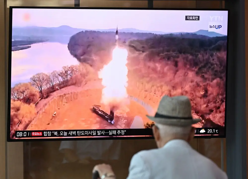 A man watches a television screen showing a news broadcast with file footage of a North Korean missile test | AFP