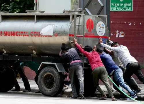 New Delhi Municipal Corporation (NDMC) workers move a water tanker amid heatwave and water crisis, in New Delhi. l Photo: PTI