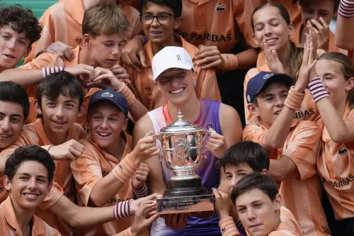 Ball kids pose with Poland's Iga Swiatek who holds the trophy after winning the women's final of the French Open tennis tournament against Italy's Jasmine Paolini at the Roland Garros stadium in Paris, France. l Photo: AP