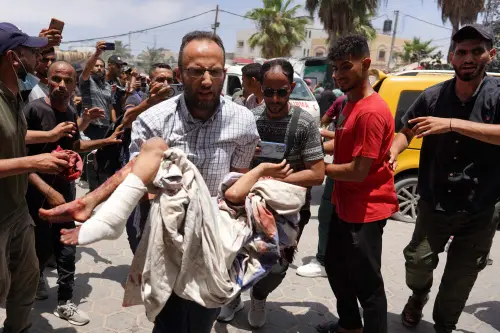 A man rushes carrying an injured child following the Israeli bombardment of a residential apartment in Deir al-Balah and of al-Maghazi, as he arrives at the al-Aqsa Martyrs Hospital in Deir al-Balah, in the central Gaza Strip. l Photo: AFP