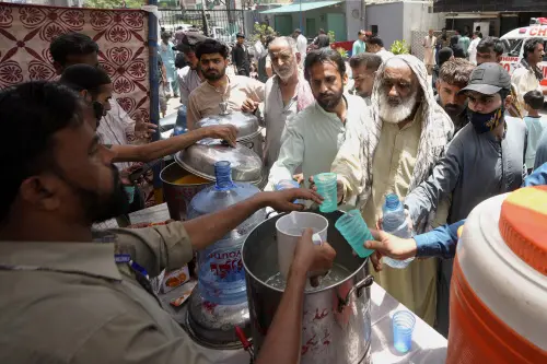 Volunteers provide lime sugar water to people at a camp set up to prevent heat stroke on a hot summer day, in Karachi, Pakistan. l Photo: AFP