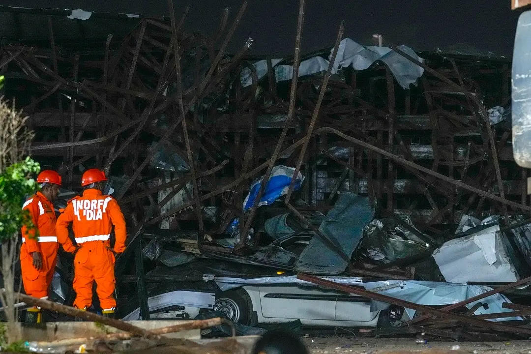 Rescuers look for victims under a billboard that collapsed following heavy rain | Photo: AP