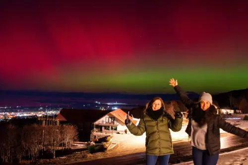 Women pose for pictures as the Aurora Australis, also known as the Southern Lights, glow on the horizon as seen from Ushuaia, Tierra del Fuego, Argentina. l Photo: AFP