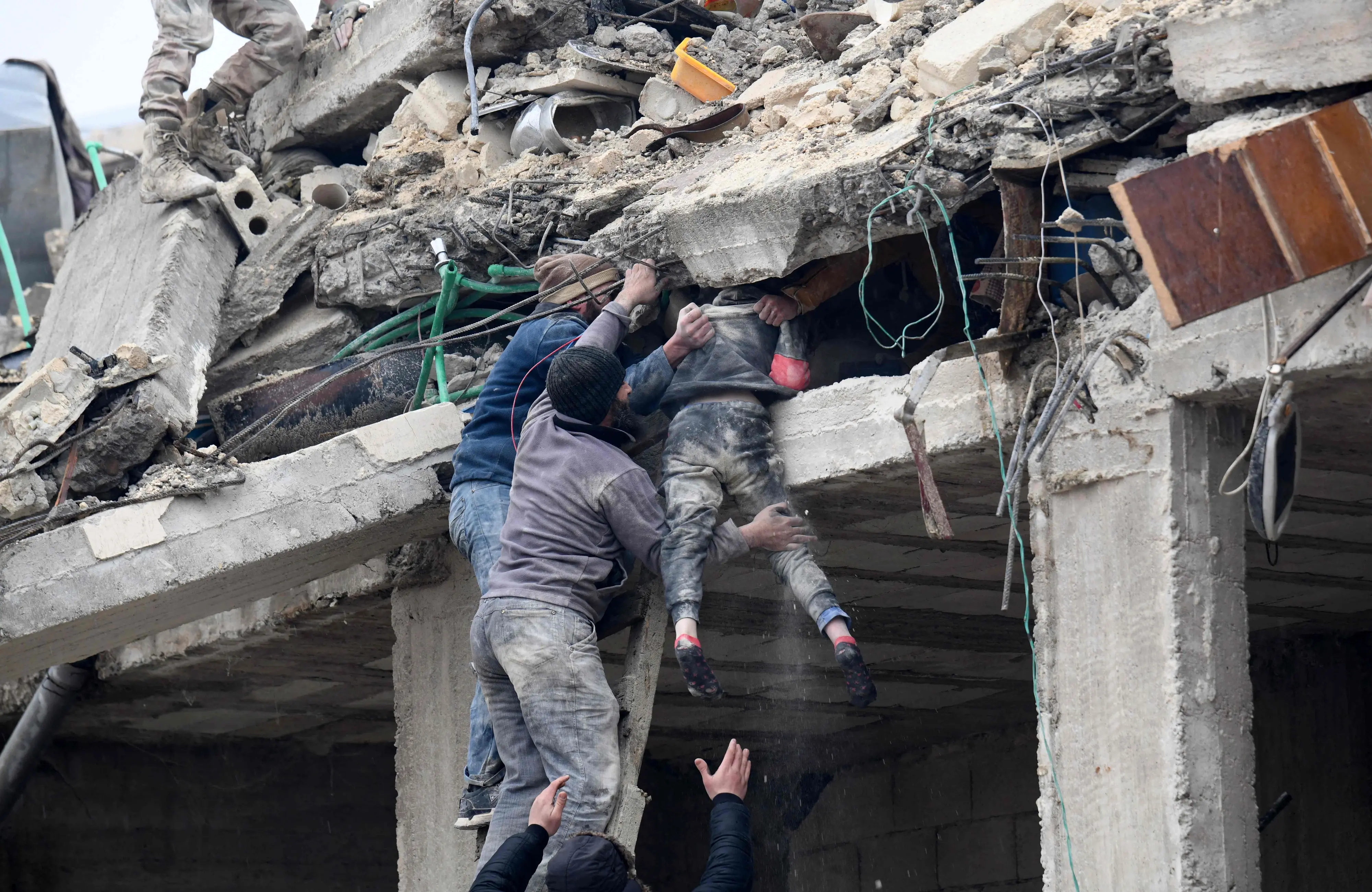 Residents retrieve an injured girl from the rubble of a collapsed building in Syria | Photo: AFP