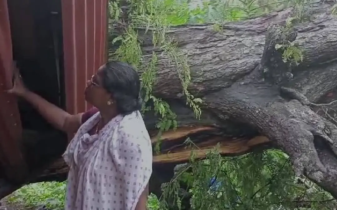 Ramani besides her damaged house.