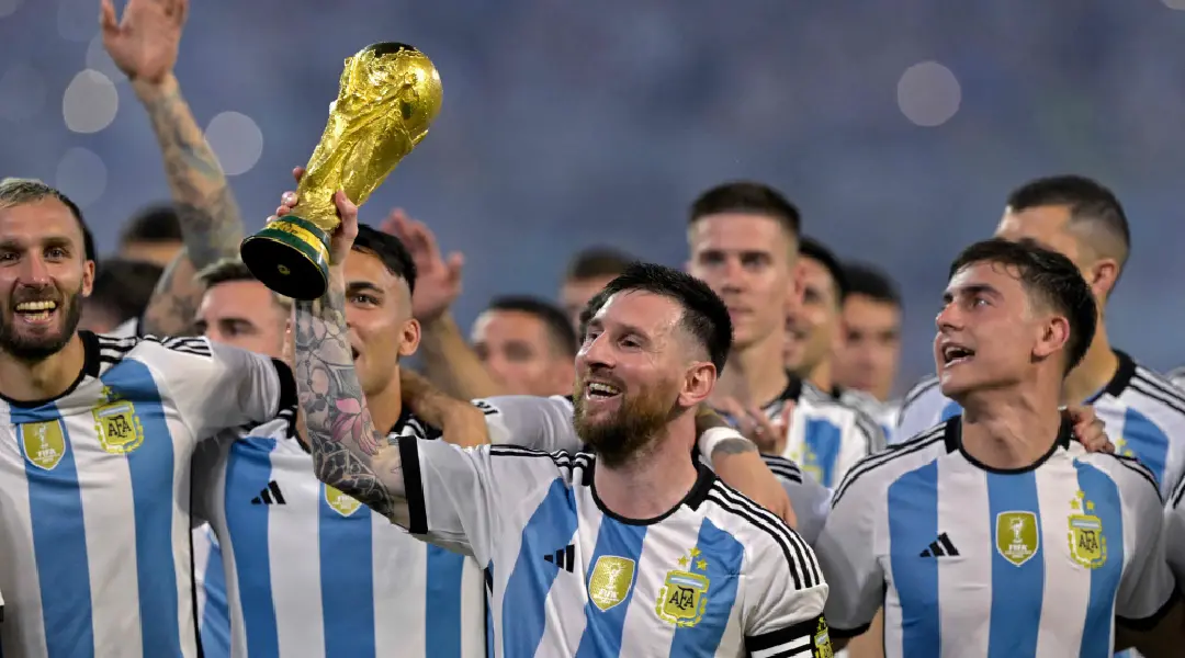 Lionel Messi holding the FIFA World Cup, his teammates in the background. I Photo: AFP