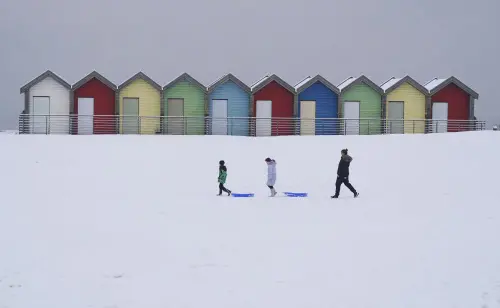 People walk through the snow beside the beach huts at Blyth in Northumberland, England, Sunday, Dec. 3, 2023 as temperatures are tipped to plunge to as low as minus 11C (12.2 F) in parts of the UK over the weekend. Photo: AP