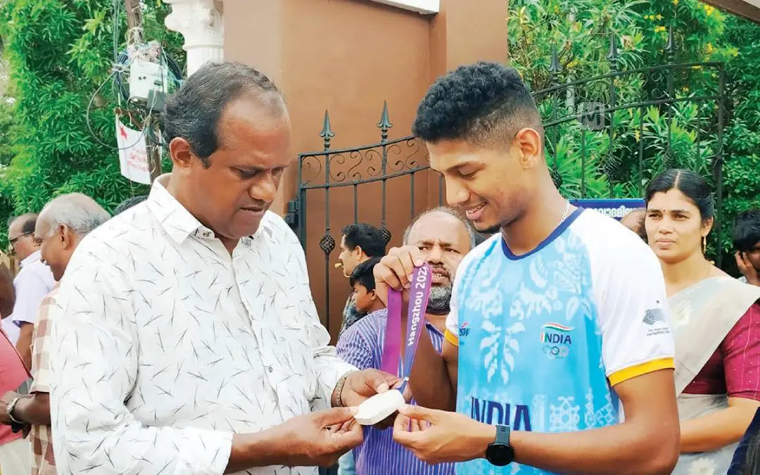 Afsal showing his Asian Game's medal to his beloved teacher Manoj.