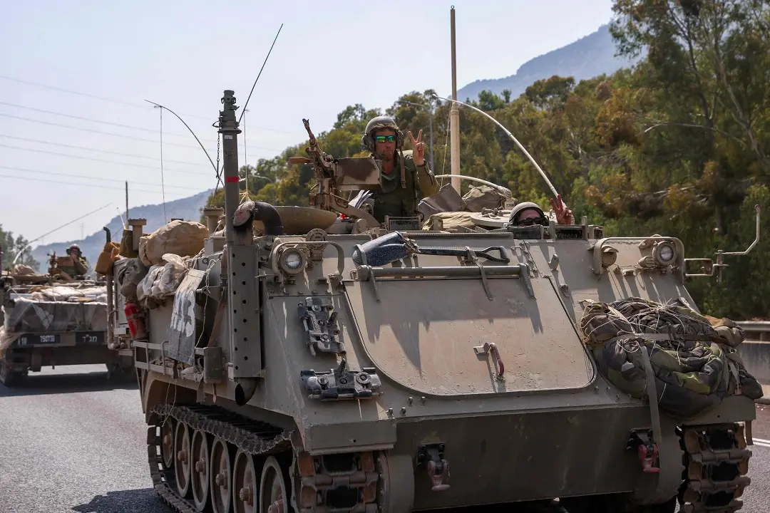 An Israeli soldier in a Merkava tank gestures the victory sign on the outskirts of the northern town of Kiryat Shmona near the border with Lebanon on October 8, 2023. Lebanon's Hezbollah and Israel said they traded cross-border fire on October 8, as Israel fought the Shiite movement's ally Hamas on its southern flank a day after militants from the Palestinian group stormed its Gaza frontier. (Photo by JALAA MAREY / AFP)