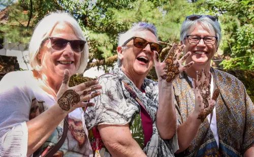 Tourists pose for photos showing their hands after applying 'henna' during celebrations of World Tourism Day, in Kochi, Tuesday, Sept. 27, 2022 | Photo: PTI