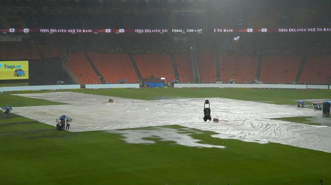 Groundsmen hold umbrellas near the covered pitch as it rains ahead of the IPL 2023 final cricket match between Gujarat Titans and Mumbai Indians | Photo: PTI