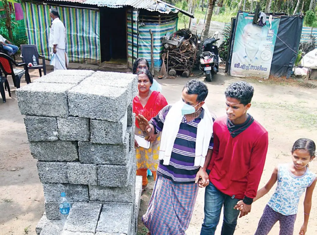 Chithra, husband Dhanesh, son Dhanoop, and daughter Neena next to the construction materials brought for building their new house