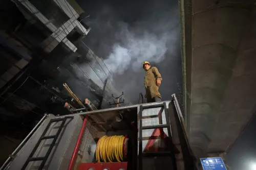 A fire official stands on a fire brigade truck to help his colleagues douse a fire in a four storied building, in New Delhi, India, Saturday, May 14, 2022 | Photo: AP