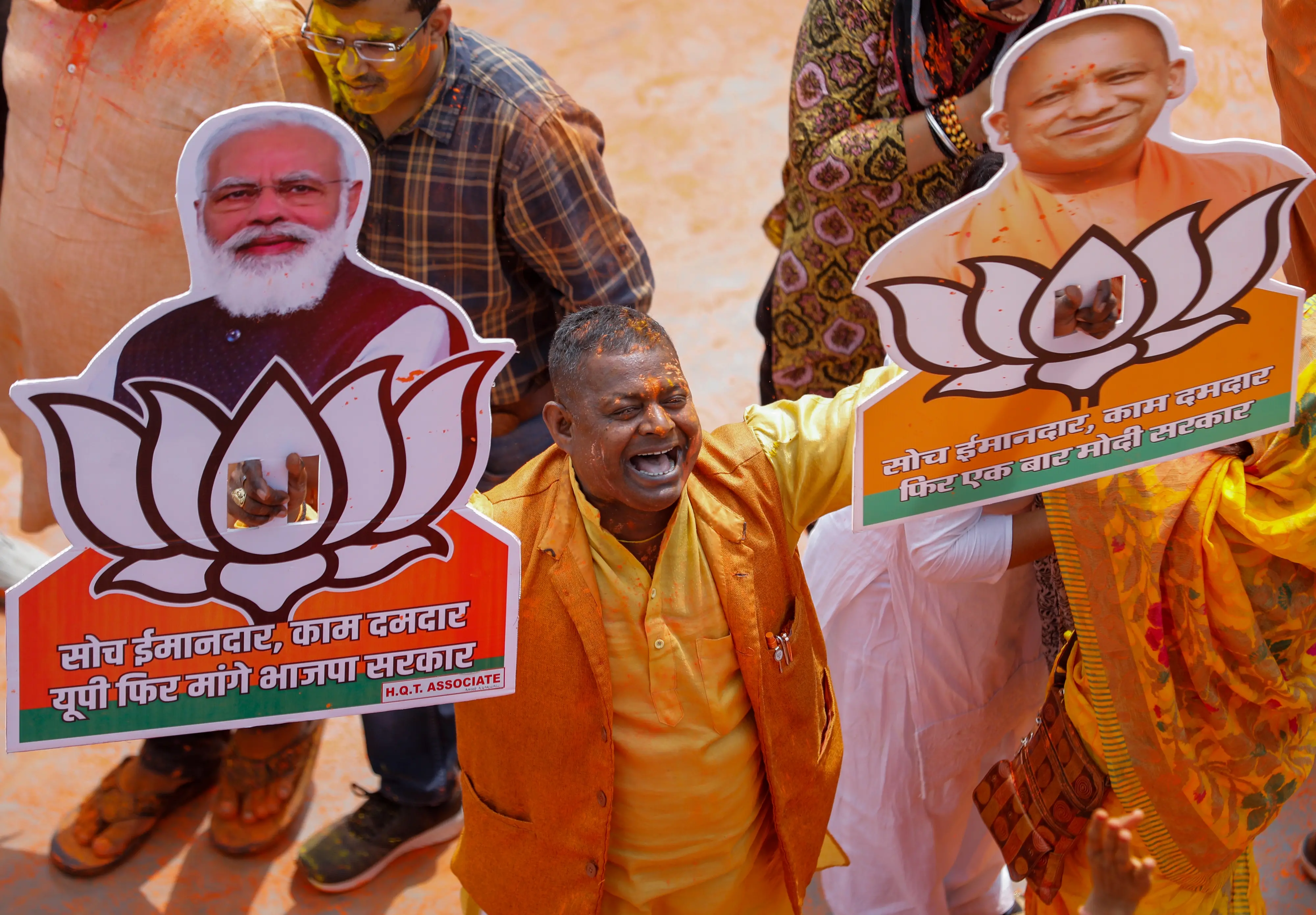 A Bharatiya Janata Party (BJP) worker displays party symbol with photographs of Prime Minister Narendra Modi, left and Uttar Pradesh Chief Minister Yogi Adityanath as they celebrate early leads for the party in Uttar Pradesh state elections in Lucknow. Photo:AP