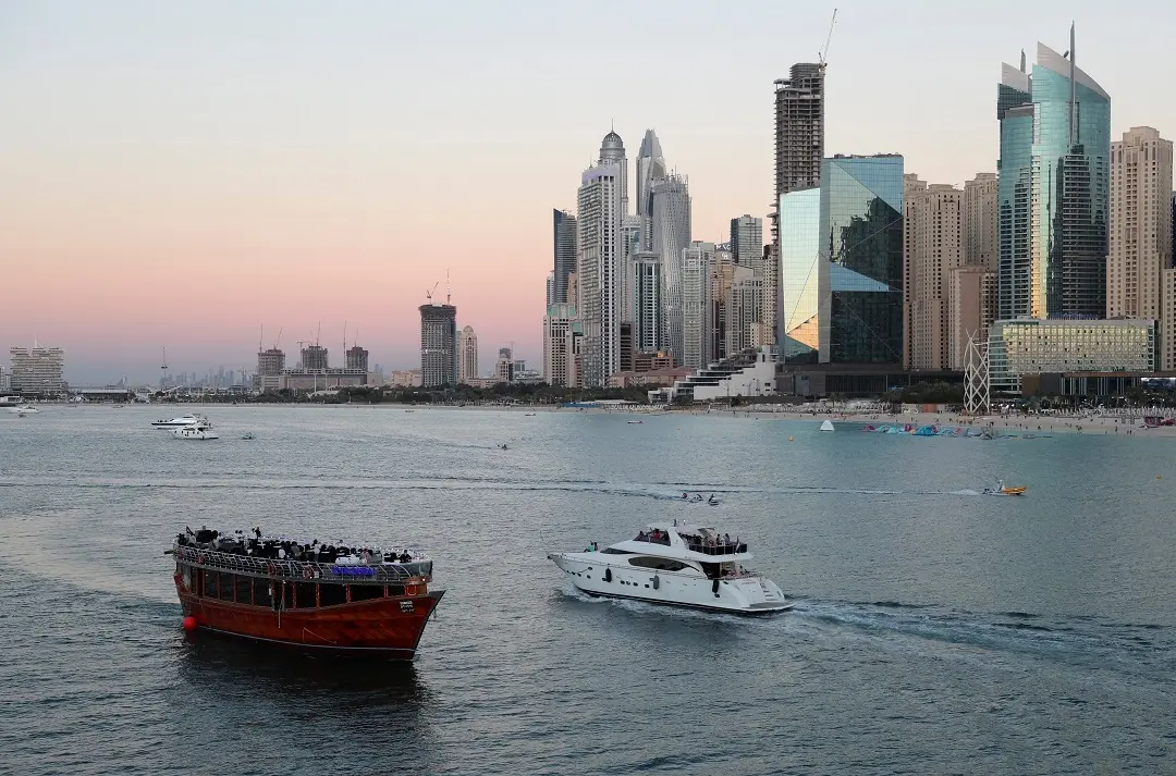 Tourists on a yacht as they pass a traditional dhow serving a dinner cruise, in Dubai, United Arab Emirates | Photo: AP