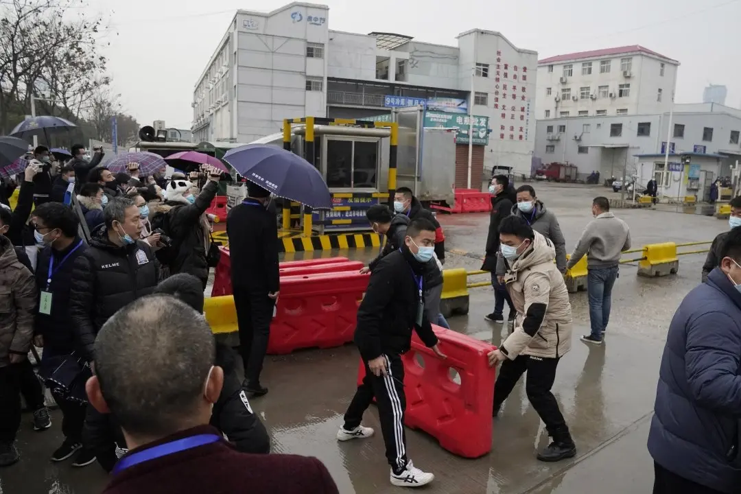 Security personnel use barriers to block the way after the World Health Organization team arrive at the Baishazhou wholesale market on the third day of field visit in Wuhan in central China's Hubei province on Sunday| AP