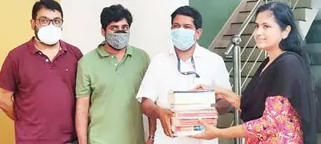 Edavanna panchayat president T Abhilash handing over books to Ranjini Ramu, a teacher at Edavanna high school, after she won the book chit