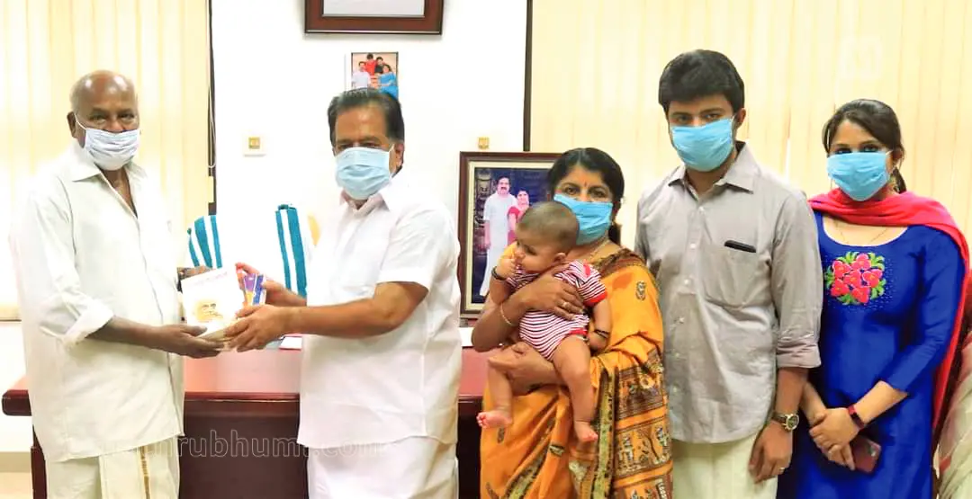 Ramesh Chennithala handing over books to writer Perumbadavam Sreedharan. Chennithala's wife Anitha, son Ramith, daughter-in-law, grandchild also are seen.