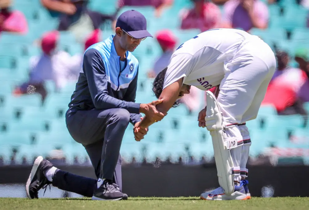 India's Rishabh Pant is assisted by a trainer after being hit by a short delivery from Australia's Pat Cummins during day three of the third cricket Test match between Australia and India at the Sydney Cricket Ground | AFP