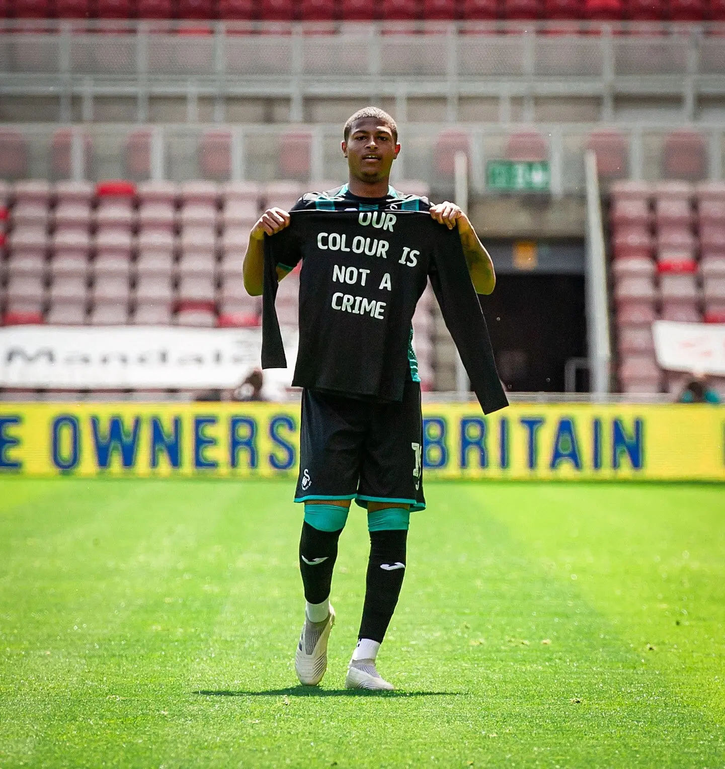 Swansea's on-loan striker Rhian Brewster celebrating the first of his goals in a 3-0 win at Middlesbrough by holding up a shirt with the words 'Our Colour Is Not A Crime' written on it. (Photo: Twittter|Rhian Brewster)