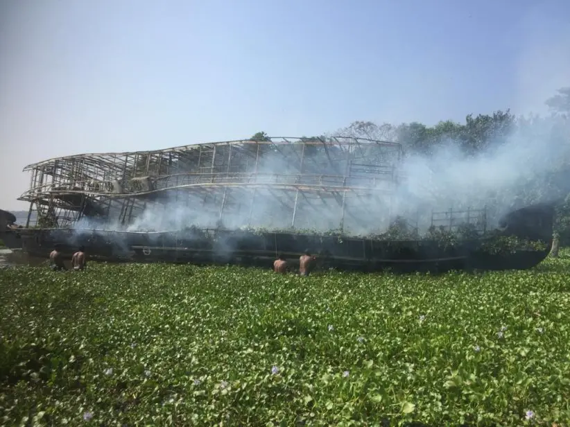 People trying to douse the blaze on a houseboat in Alappuzha