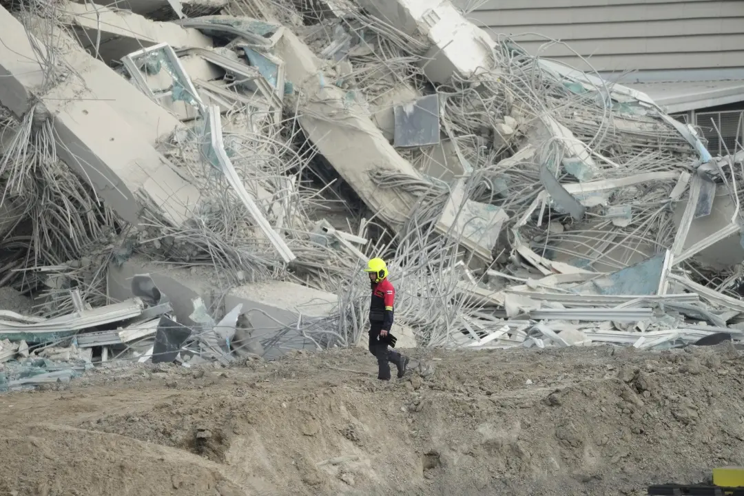 A rescuer walks past debris of a construction site for a high-rise building in Bangkok | Photo: AFP