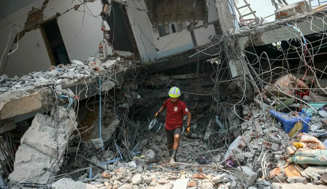 A rescuer carries equipment as a team searches through the rubble of a destroyed building in Myanmar(Photo: AFP)