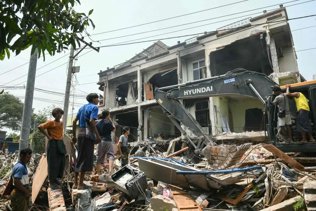 Heavy construction equipment is used to dig through the rubble as people look for survivors in a damaged building in Mandalay a day after an earthquake struck central Myanmar | Photo: AFP