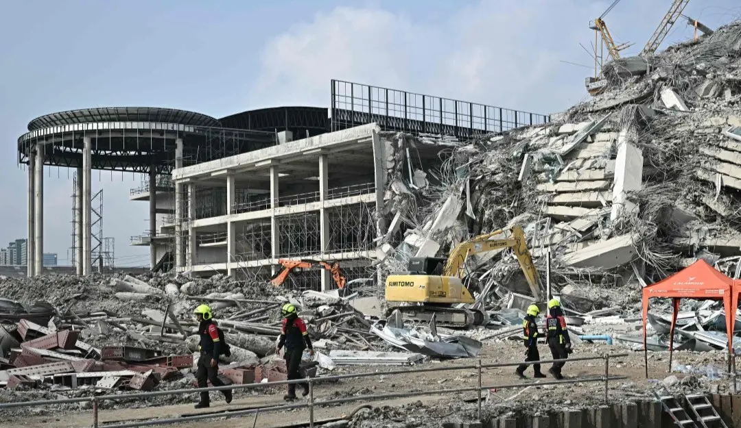 Machinery is moved on the site of an under-construction building collapse in Bangkok
