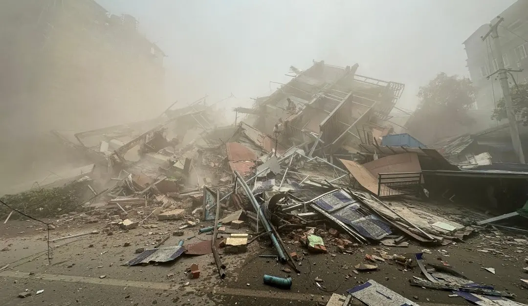 People inspect the debris of a collapsed building in Mandalay