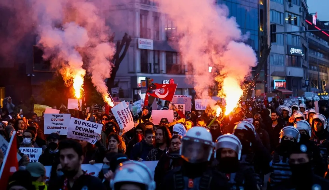 Protestors hold red flares and rallies in front of Turkish anti-riot police officers in Istanbul.