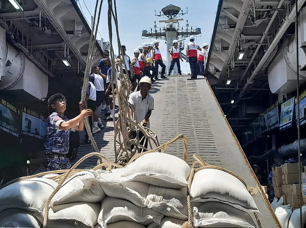 This handout photograph released by India's Ministry of External Affairs shows officers unloading sacks of aid donated by India to its earthquake-hit neighbour Myanmar upon its arrival at the Thilawa Port along the Yangon river | AFP