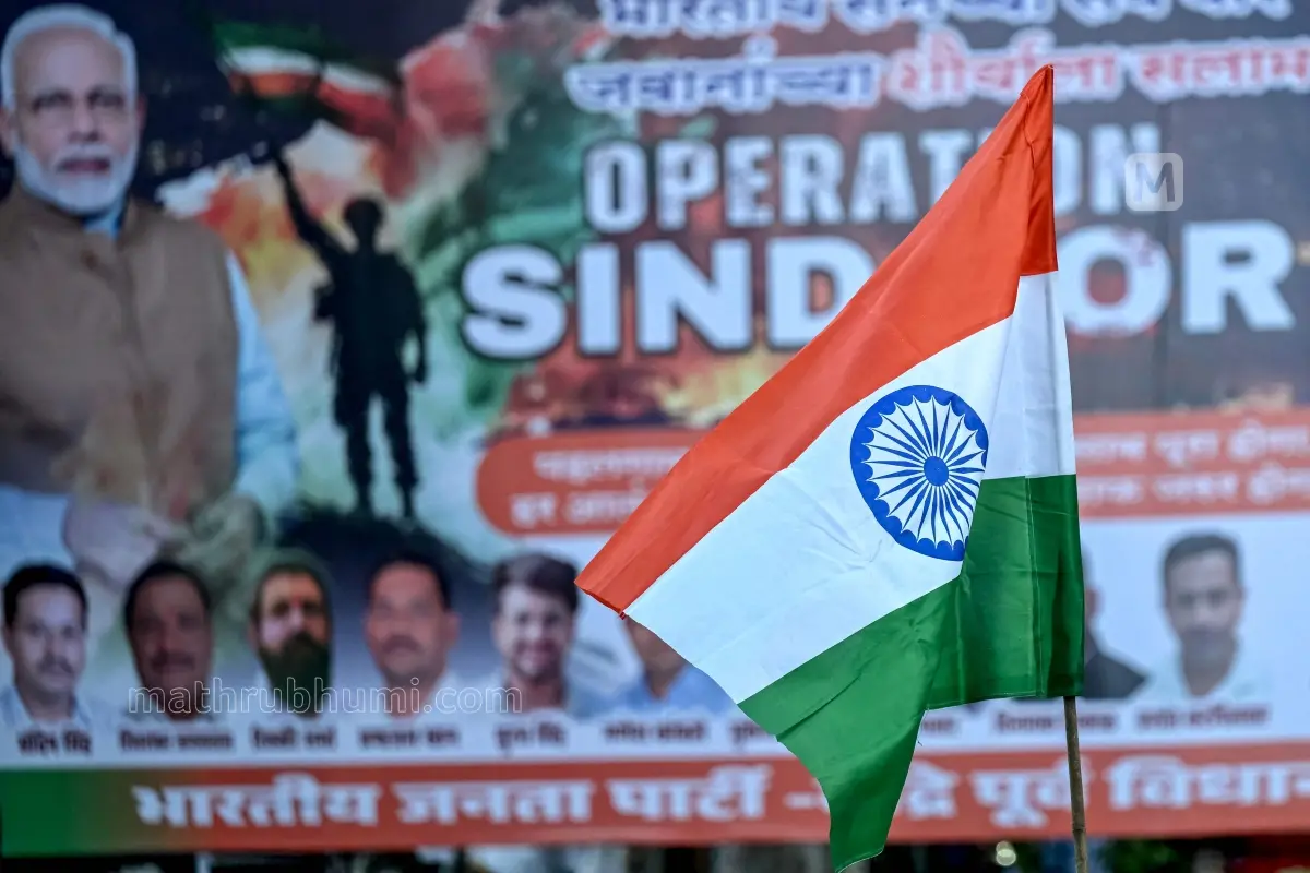 An activist holds the national flag of India in front a banner that praises the Indian defence forces for their military operation, code-named 'Operation Sindoor'