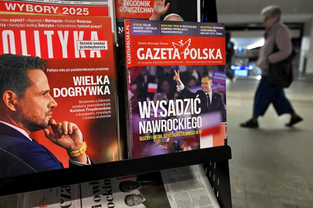 A woman walks through an underground passage past a kiosk selling magazines with covers depicting presidential candidates for the 2025 Polish presidential election Rafal Trzaskowski (L) and Karol Nawrocki (R) in Warsaw