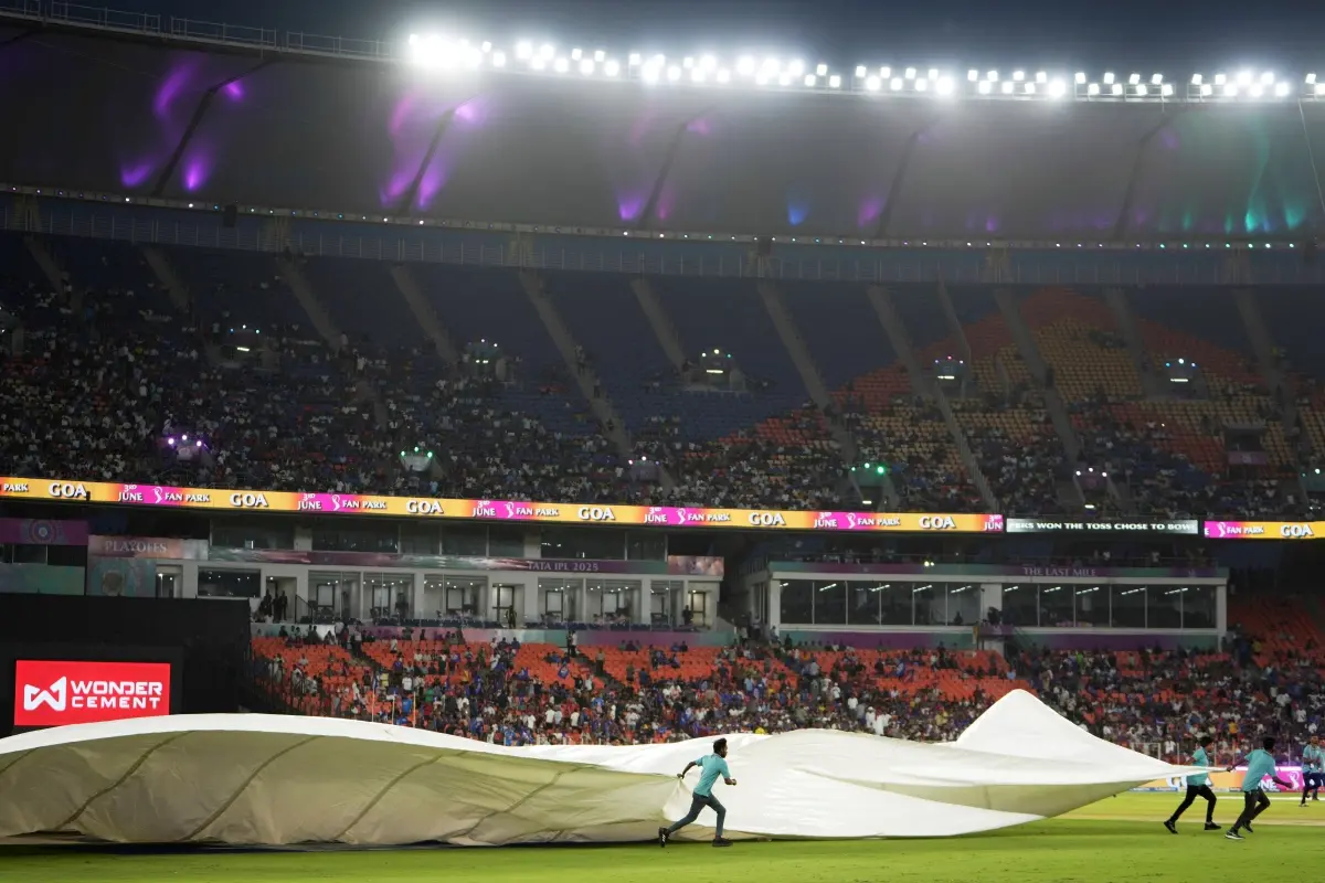 Groundsmen run with the covers after rain delays the play of the Indian Premier League cricket match between Punjab Kings and Mumbai Indians at Narendra Modi Stadium in Ahmedabad. | Photo: AP