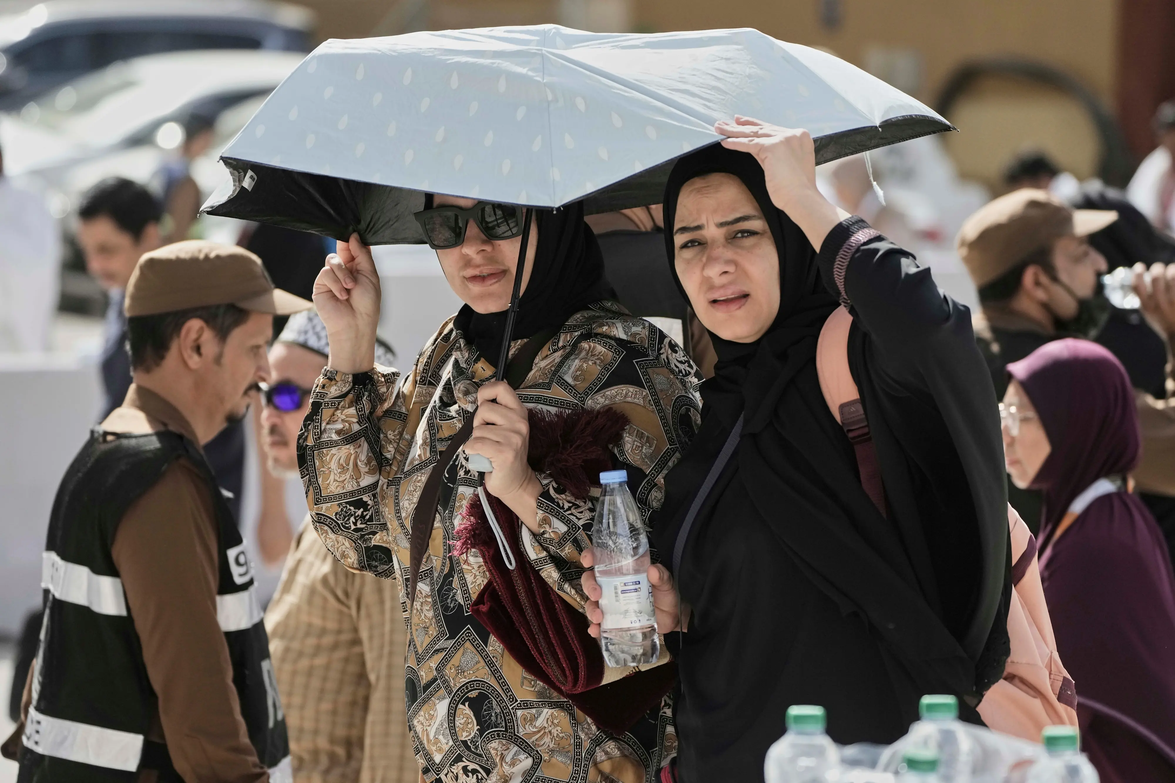 Egyptian pilgrims share an umbrella outside the Grand Mosque during the annual hajj pilgrimage at the holy city of Mecca, Saudi Arabia. | Photo: AP