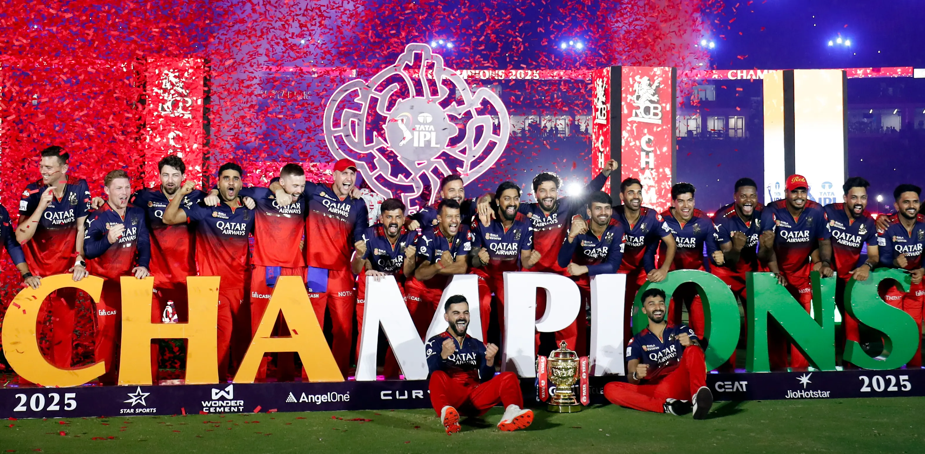 Royal Challengers Bengaluru's captain Rajat Patidar, Virat Kohli and others pose for photographers with the championship trophy.