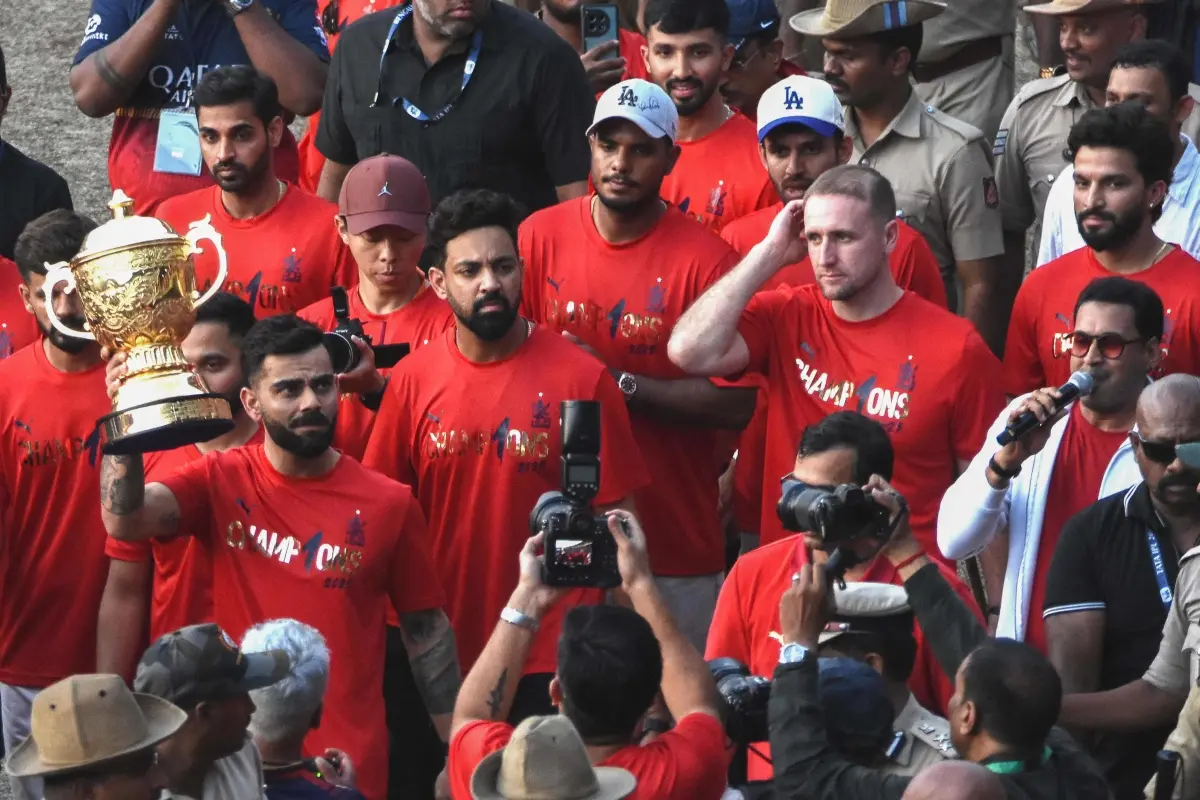 Royal Challengers Bengaluru's Virat Kohli (L) holds the Indian Premier League trophy aloft alongside teammates outside the M. Chinnaswamy Stadium as they celebrate with fans winning the Indian Premier League (IPL) title in Bengaluru. | Photo: AFP