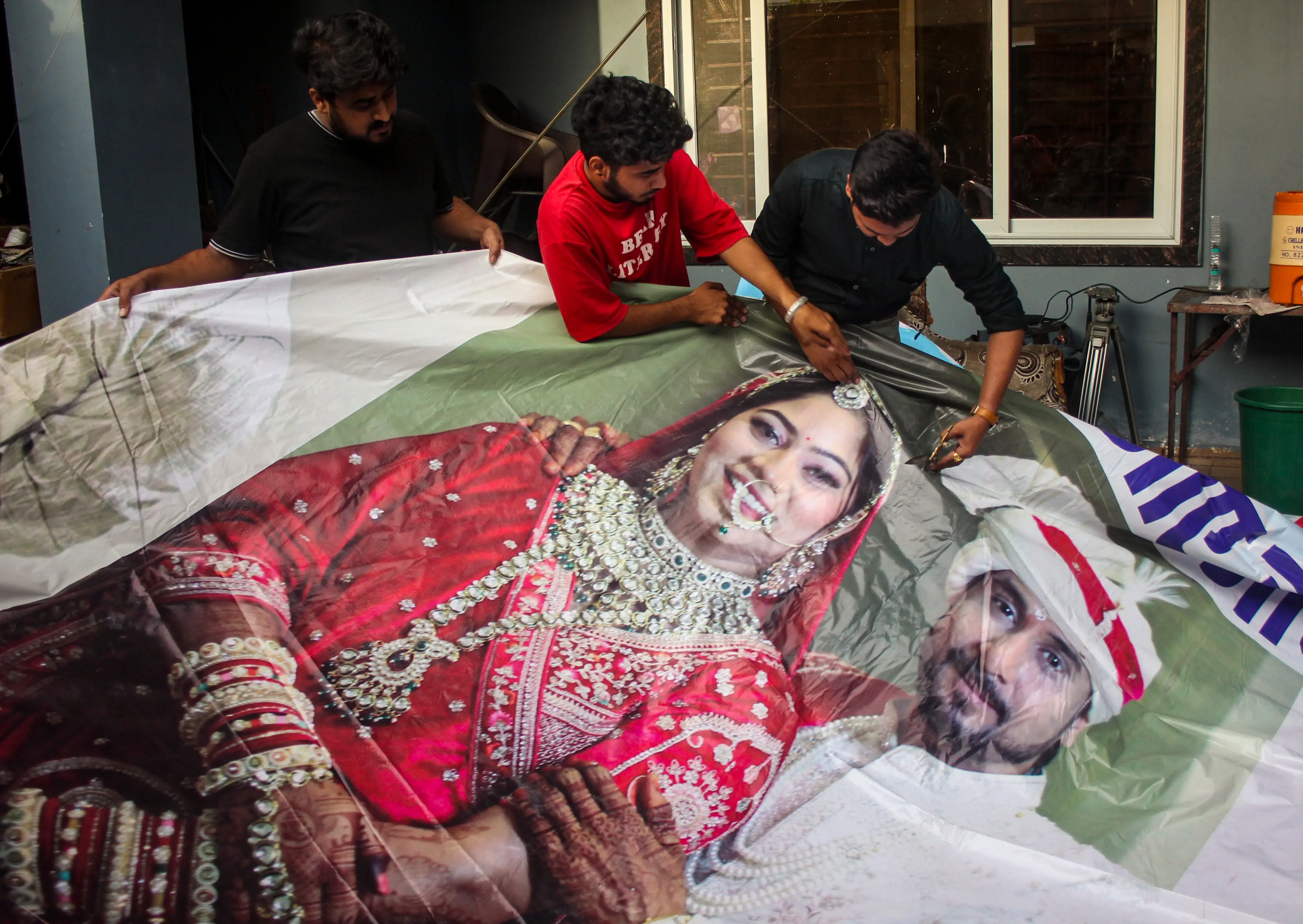 Family members of Raja Raghuvanshi, who was allegedly murdered during his honeymoon in Meghalaya, cut out the picture of his wife Sonam Raghuvanshi from a poster of their marriage | PTI