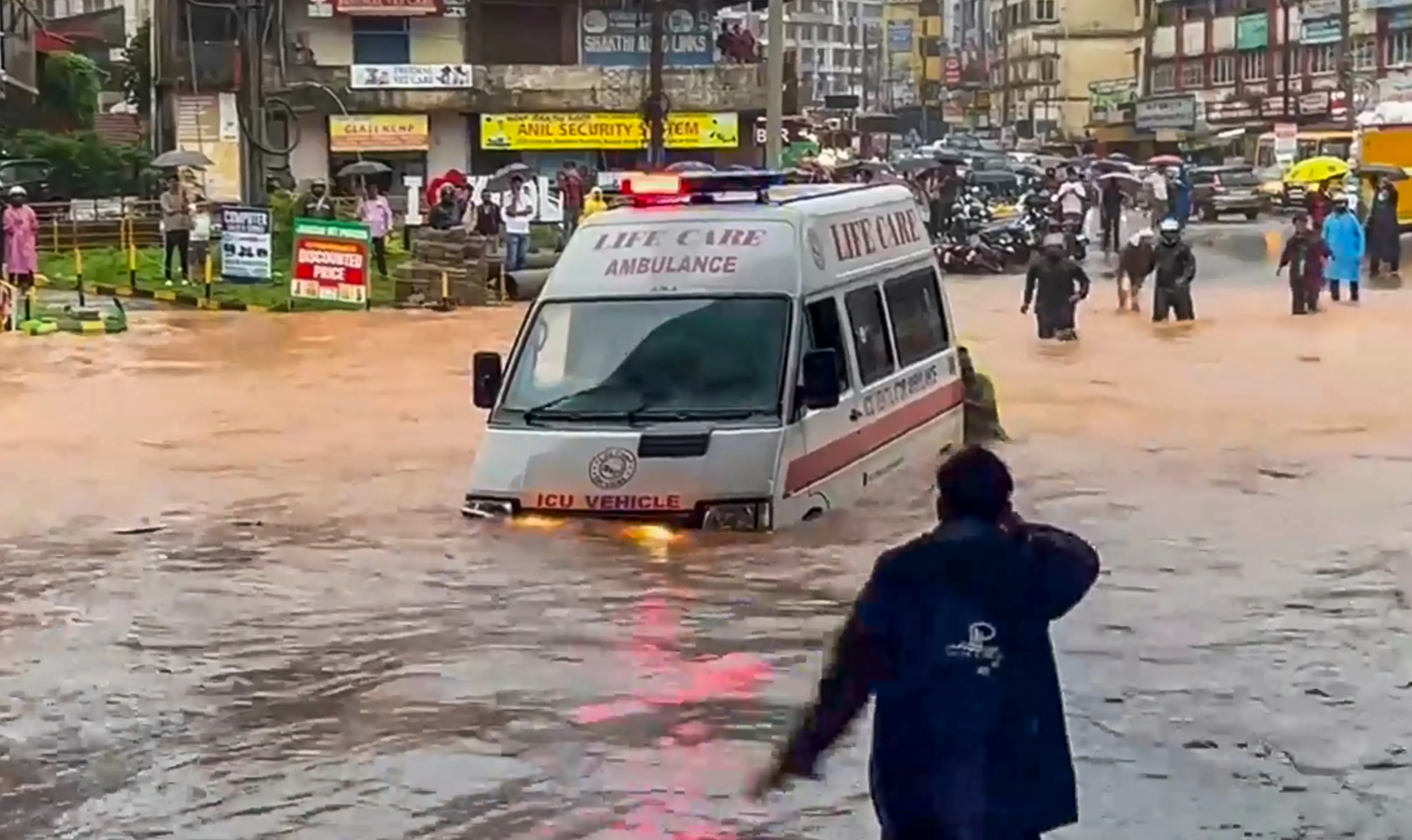 People push an ambulance while wading through a waterlogged road amid rainfall in Mangaluru | PTI