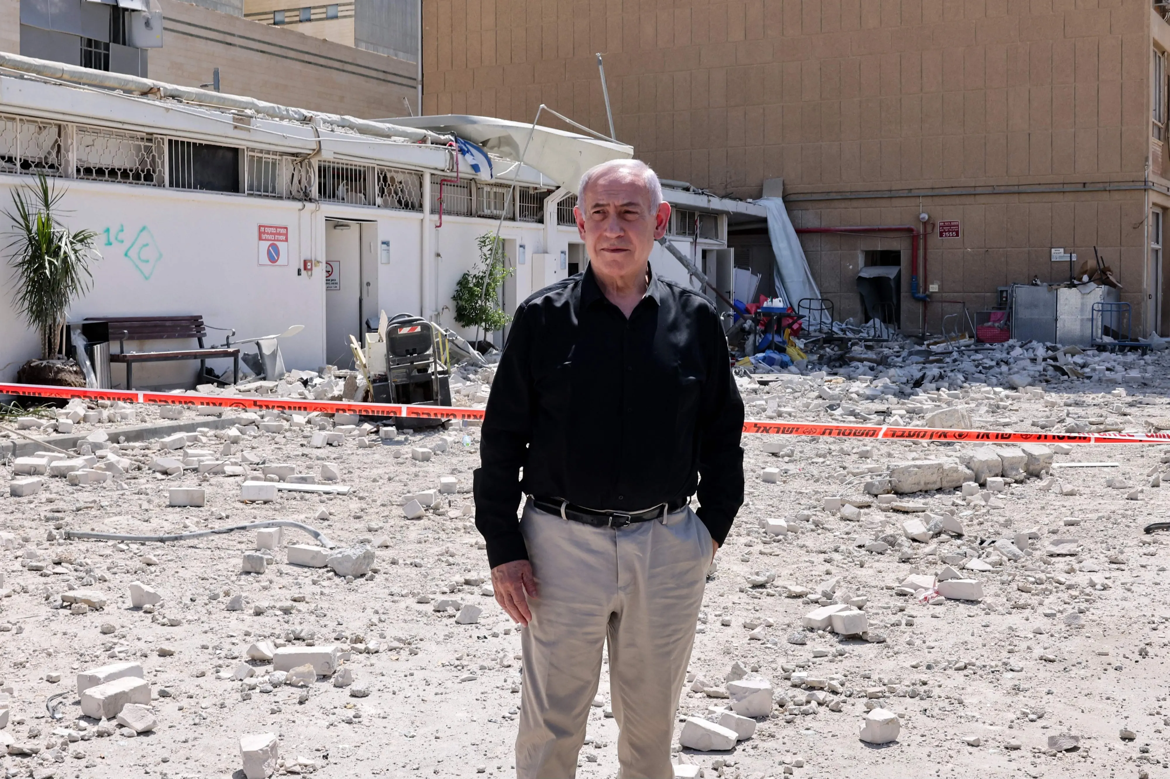Israeli Prime Minister Benjamin Netanyahu stands amid debris outside the Soroka Hospital in the southern city of Beersheba, after it was hit by a missile fired from Iran. | Photo: AFP